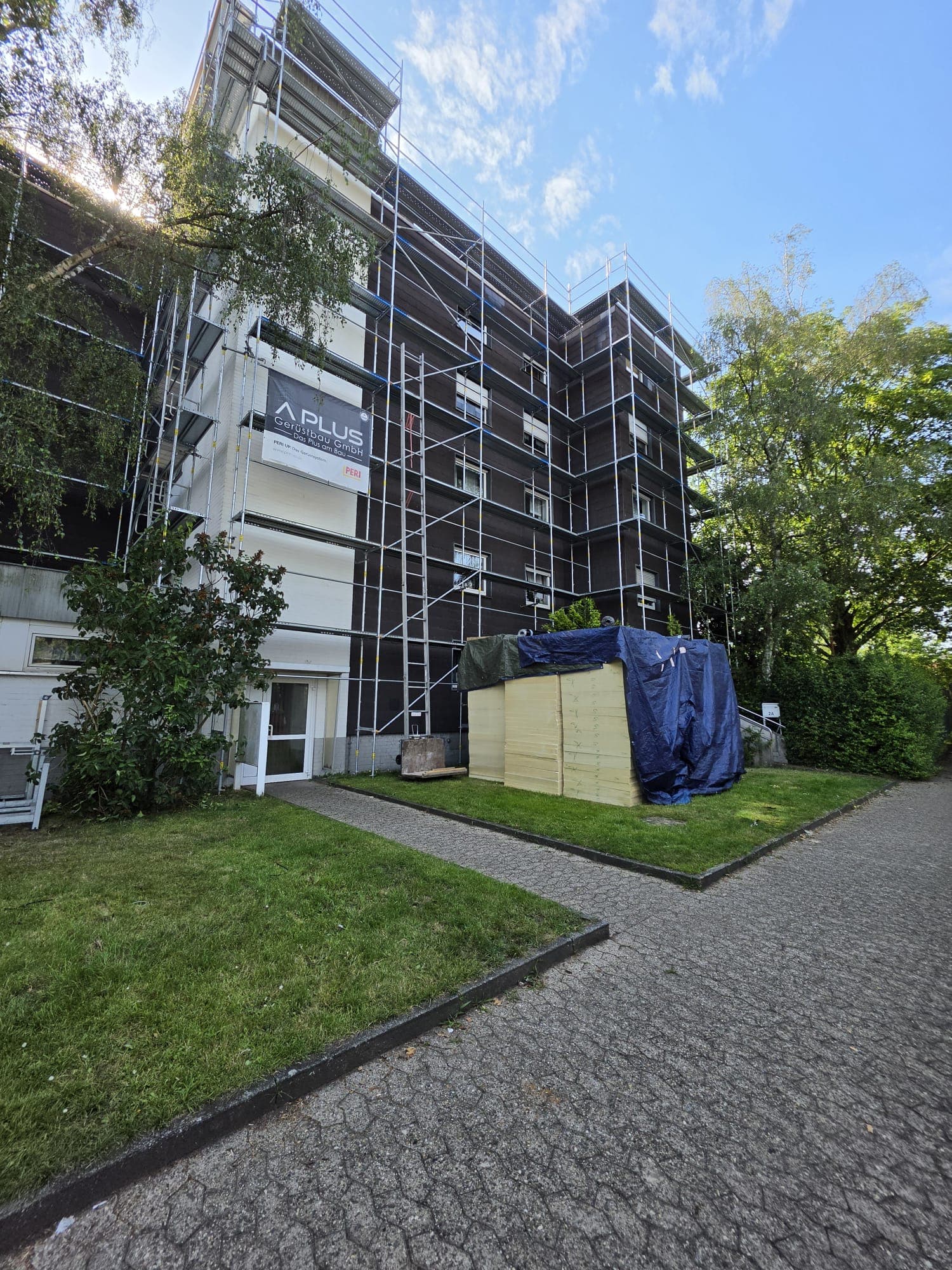 Eingerüstetes Wohnhaus mit Firmenbanner der A PLUS Gerüstbau