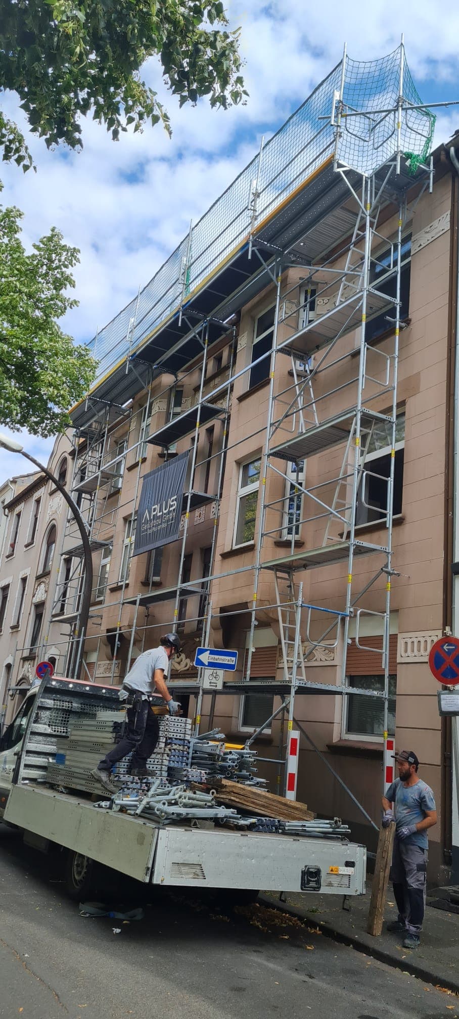 Gerüstbauer entladen Material vor einem eingerüsteten Altbau