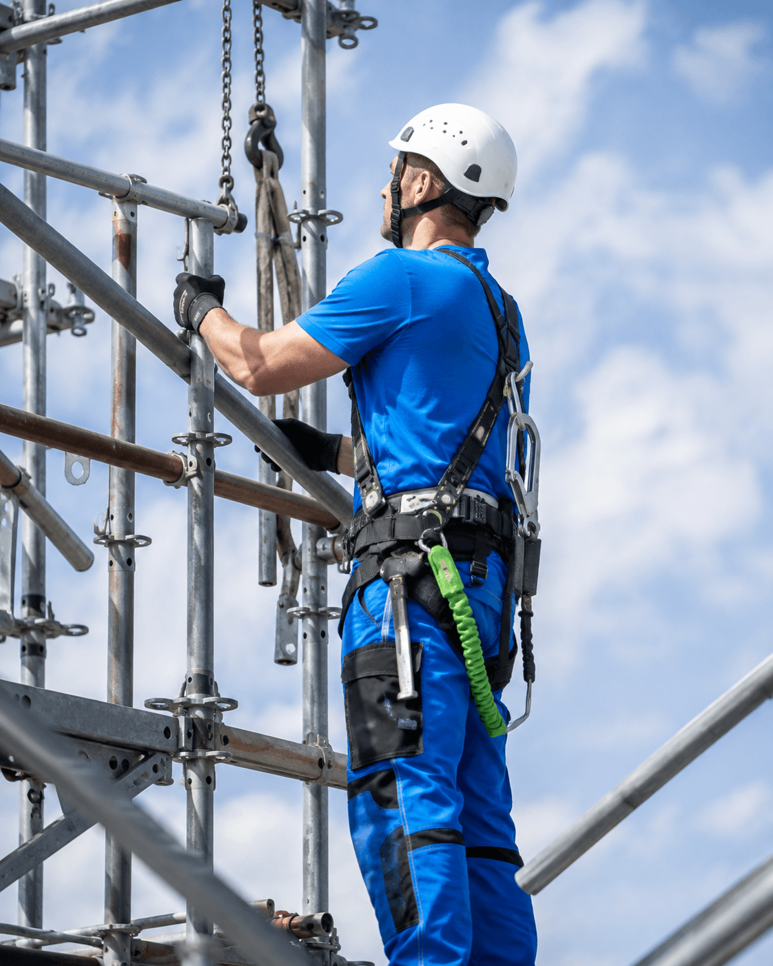 Gerüstbaumitarbeiter im Porträt vor einem eingerüsteten Gebäude