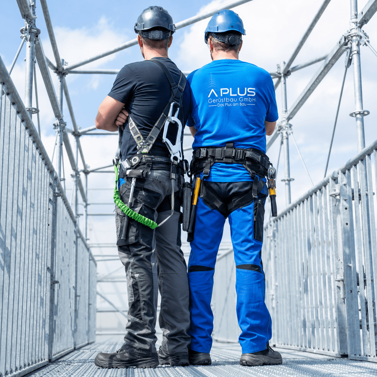 Gerüstbaumitarbeiter von hinten vor einem eingerüsteten Gebäude